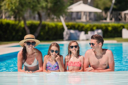 Happy family of four in swimming pool