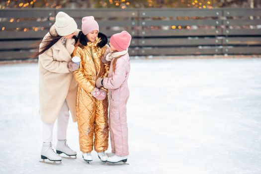 Little adorable girls with her mother skating on ice-rink
