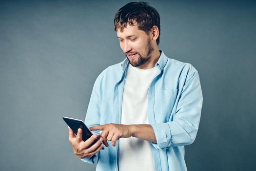 A middle-aged white Caucasian man holds a tablet in his hand and looks at a mobile application.