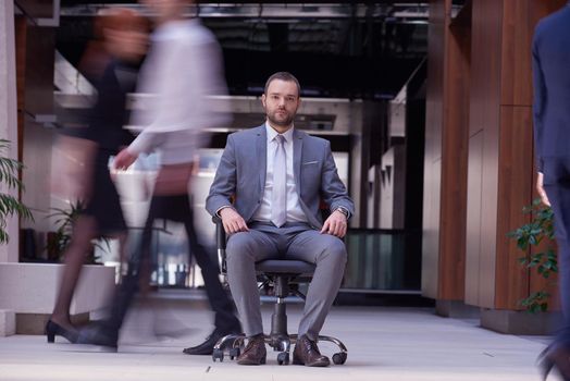 business man sitting in office chair, people group  passing by