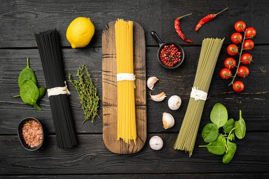 Multi colored pasta, on black wooden table background, top view flat lay