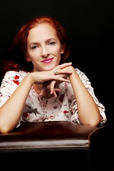 Red-haired young woman in the studio on a black background.
