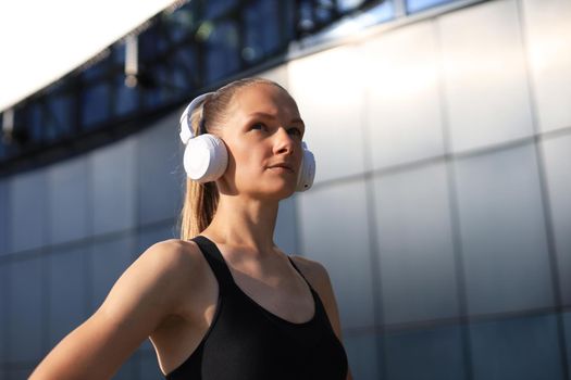 Beautiful woman in sports clothing and earphones looking aside from camera.