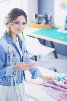 Fashion designer woman working with ipad on her designs in the studio