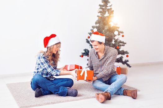 Holidays, christmas and family concept - Young happy couple opening gifts at home.