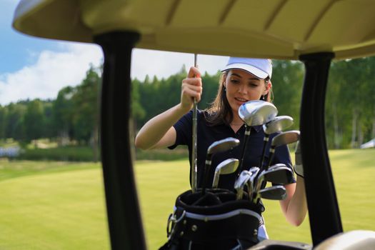 Professional woman golf player choosing the golf club from the bag.