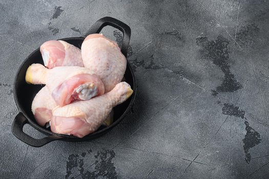 Chicken brow and drumstick with skin, in frying cast iron pan, on gray stone background, top view flat lay, with copy space for text