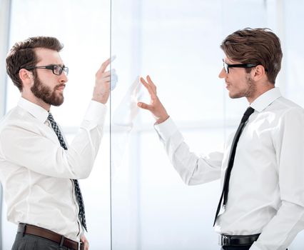 two businessmen on both sides of a glass Board