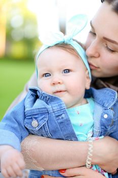 Closeup young mother kissing little daughter wearing jeans jacket.