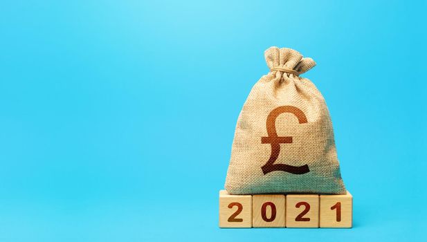 British pound sterling money bag and blocks 2021. Budget planning for next year. Beginning of new decade. Business plans and development prospects. Revenues expenses, investment and financing.