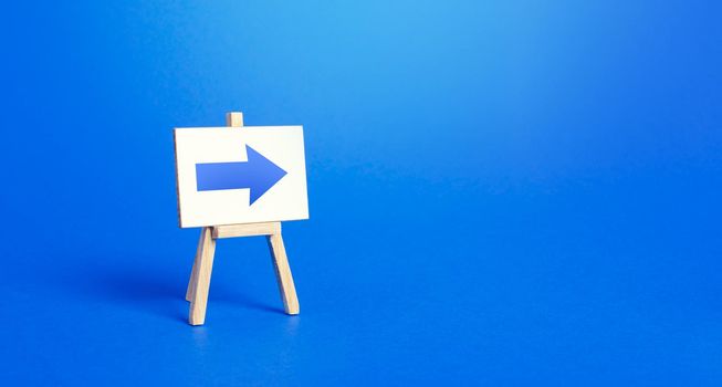 Easel with a blue right arrow. Sign of direction. Advertising of the location of a store or outlet. Minimalism. Distracting maneuver. Restriction of movement, change of course. Short road.