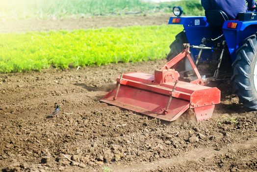 Tractor with milling machine loosens, grinds and mixes soil. Loosening the surface, cultivating the land for further planting. Farming and agriculture. Cultivation technology equipment