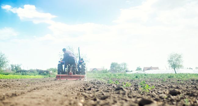 Farmer on a tractor with milling machine loosens, grinds and mixes soil. Farming and agriculture. Loosening the surface, cultivating the land for further planting. Cultivation technology equipment