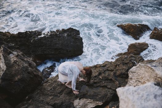 woman climbs rocky rocks by the ocean travel. High quality photo