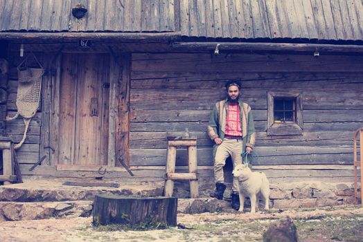 hipster with dog in front of wooden house