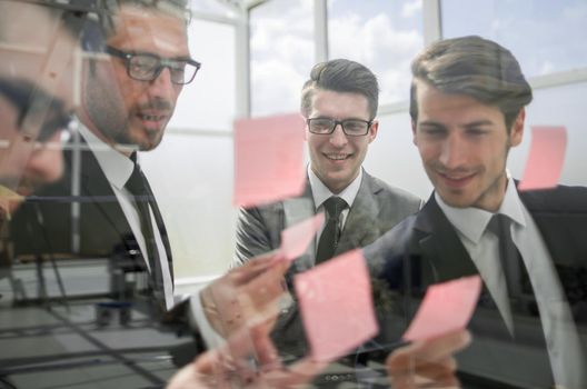 business team reading sticky notes on glass.