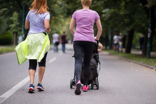 women with baby stroller jogging together