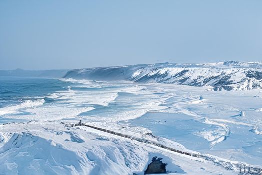 Winter wonderland and Christmas fantasy landscape. Frozen sea coast and mountains covered with snow as holiday background