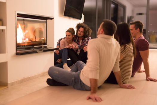 multiethnic couples sitting in front of fireplace
