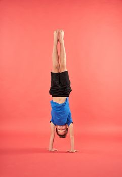 Adorable male child in sportswear doing handstand exercise