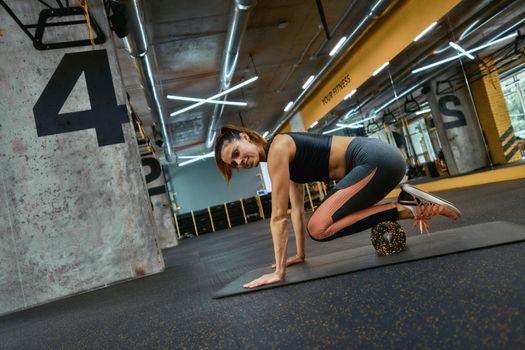 Healthy lifestyle concept. Young beautiful sportive woman in sportswear exercising with special fitness equipment at gym, using foam roller. Sportive people, training and workout concept