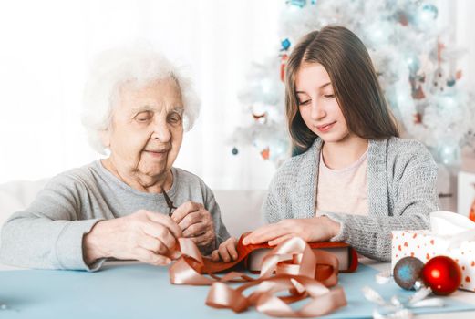 Grandmother with granddaughter decorating gifts