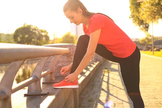 Sport woman tying sports shoes during evening run outdoors