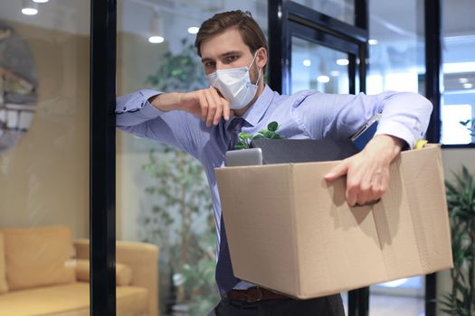 Dismissal employee in preventive medical mask in an epidemic coronavirus. Dismissed worker going from the office with his office supplies.