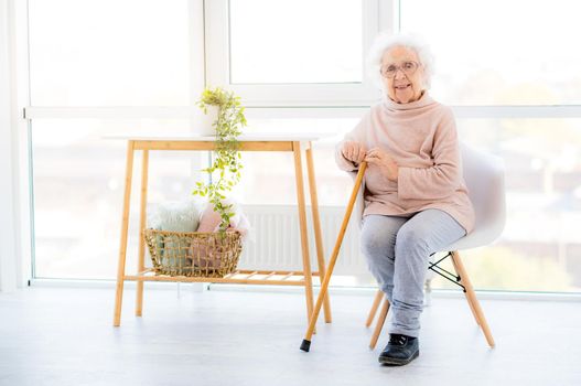 Smiling granny sitting on chair near window in living room