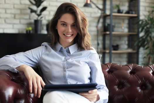 Young smiling woman with tablet pc on the sofa.