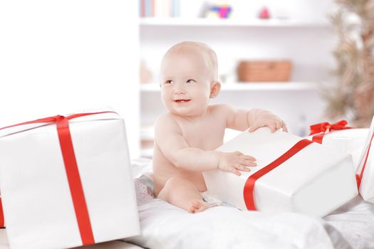 pretty baby plays with gift boxes sitting on the couch
