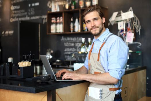Restaurant manager working on laptop, counting profit.