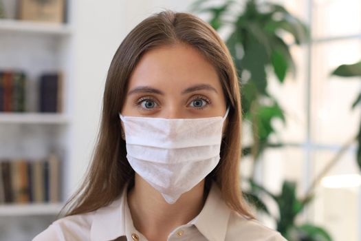 Young woman in medical mask at home during epidemic situation.