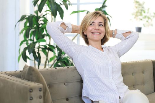 Attractive middle aged woman relaxing in sofa at home.