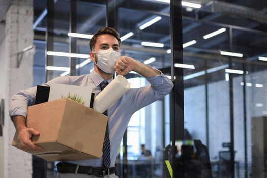 Dismissal employee in an epidemic coronavirus. Dismissed worker going from the office with his office supplies.