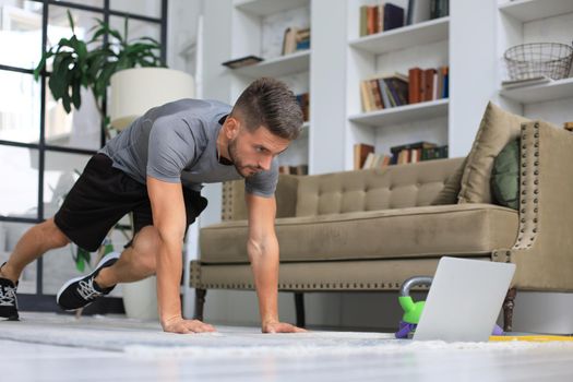 Handsome man doing sport exercise at home. Concept of healthy life.