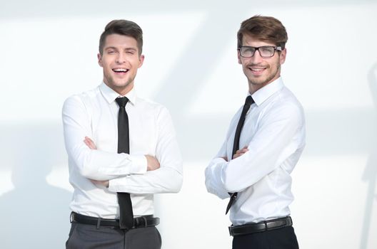 two businessmen stand with arms crossed and smile