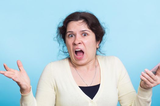 Angry aggressive woman on blue background