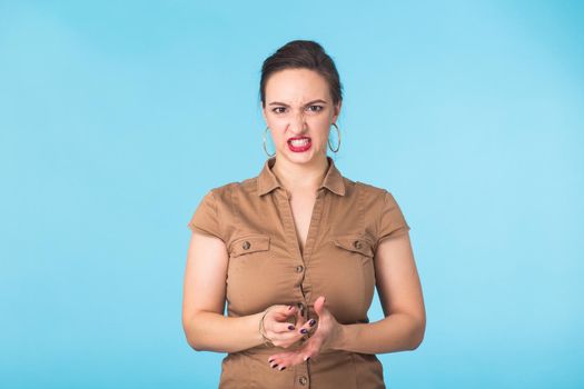 Angry aggressive woman with ferocious expression on blue background