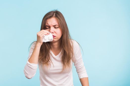 Young woman has a runny nose on blue background