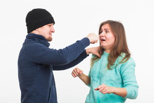 Woman victim of violence and abuse. Criminal man beats a woman on white background
