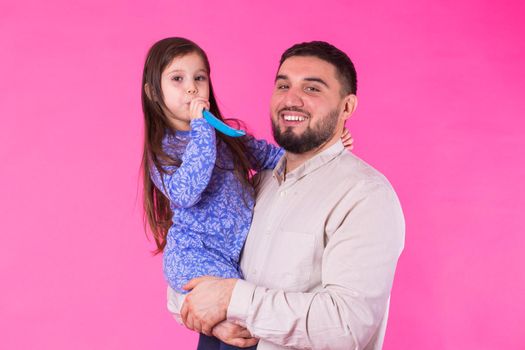 Happy father with his baby daughter on pink background