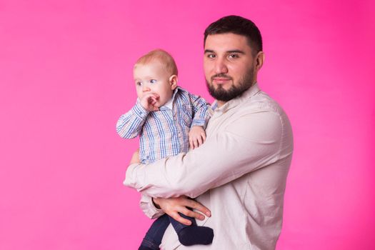Baby in the daddy hands. Pink background.