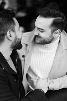Black and white photo of happy gays talking and holding hands.