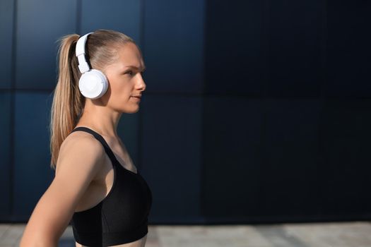 Beautiful woman in sports clothing and earphones looking aside from camera.