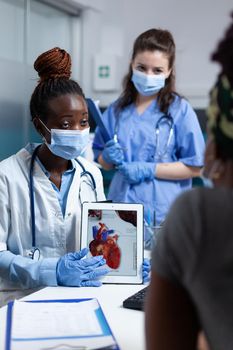 African american cardiologist doctor holding tablet showing heart radiography