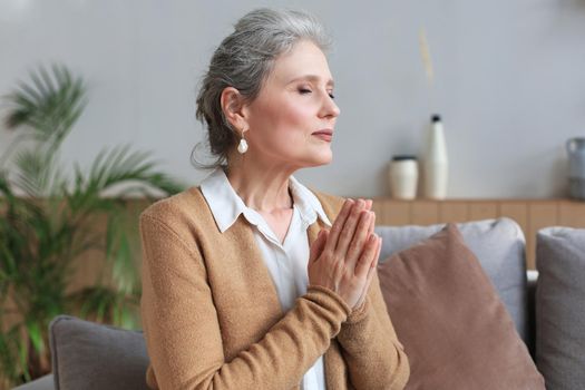 Middle aged woman praying, eyes closed, looking up, hoping for best, asking for forgiveness.