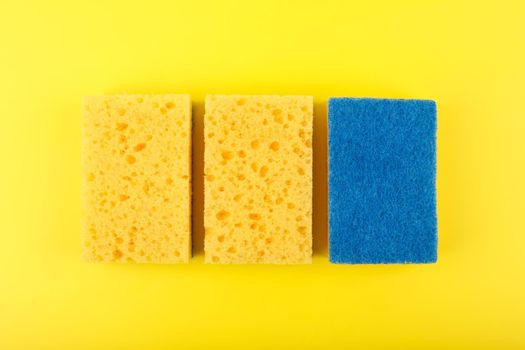 Close up of three yellow cleaning sponges on bright yellow background