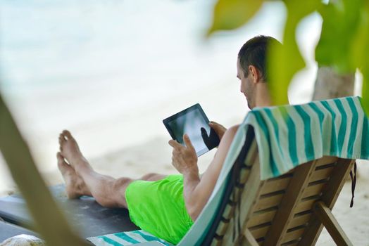 business man relaxing and use tablet computer at beautiful tropical beach