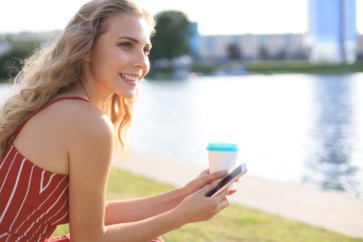 Beautiful happy smiling young woman using mobile texting messages